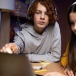 two teenage friends playing video games together home 23 2149332883